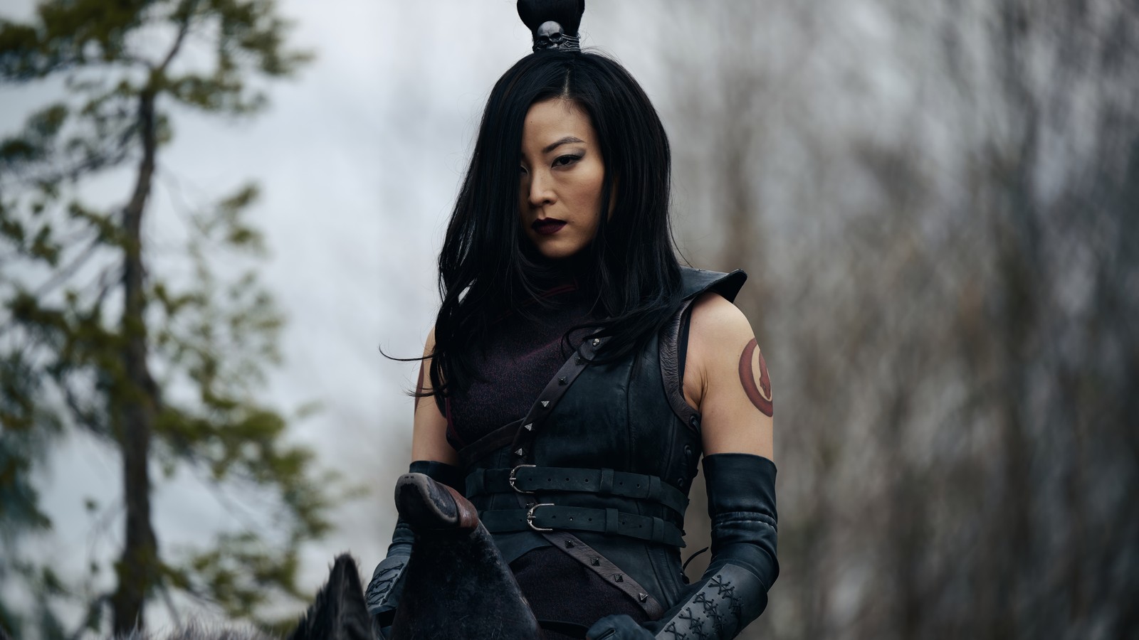 Une femme arabe en tenue en cuir noir montant un cheval dans les bois (juin, avatar le dernier maître de lair, avatar the last airbender, netflix, prise de vue réelle)