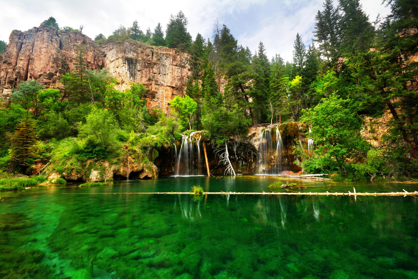 Vista de una cascada en medio de un bosque (lago, cascada, cuerpo de agua, paisaje natural, naturaleza)