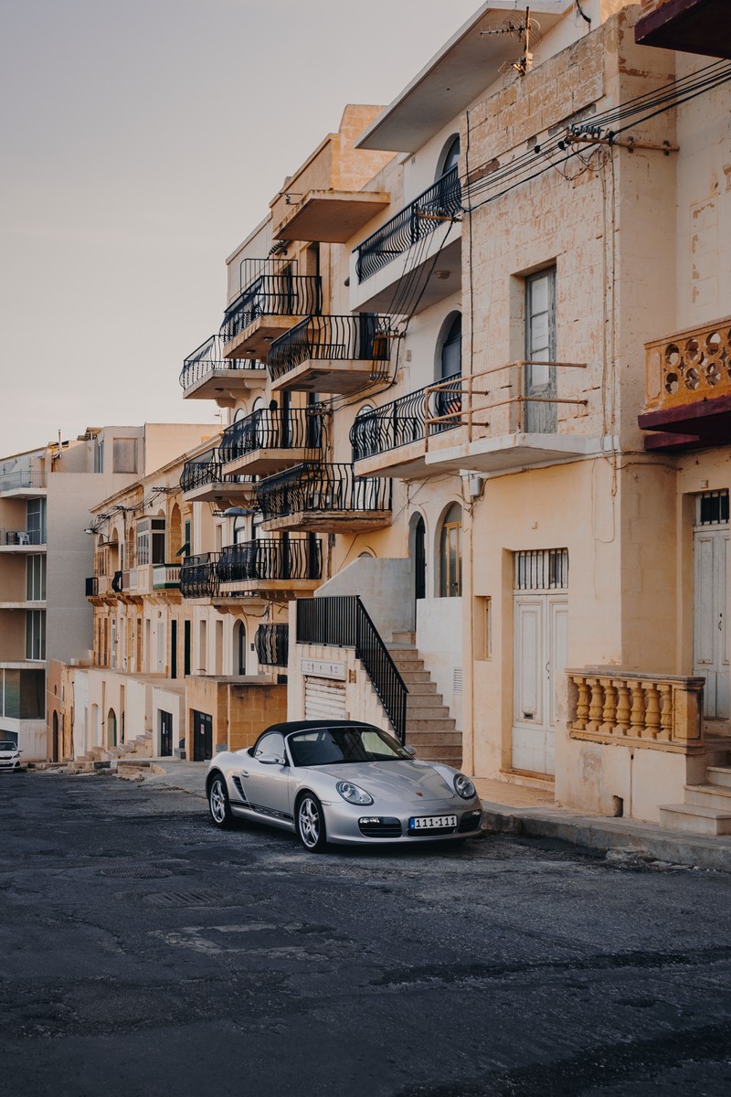 Автомобиль припаркован перед зданием с балконами (porsche, машина, здание, город, окрестности)