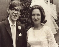 A smiling bride and groom pose together on their wedding day, showcasing classic bridal attire and elegant accessories.