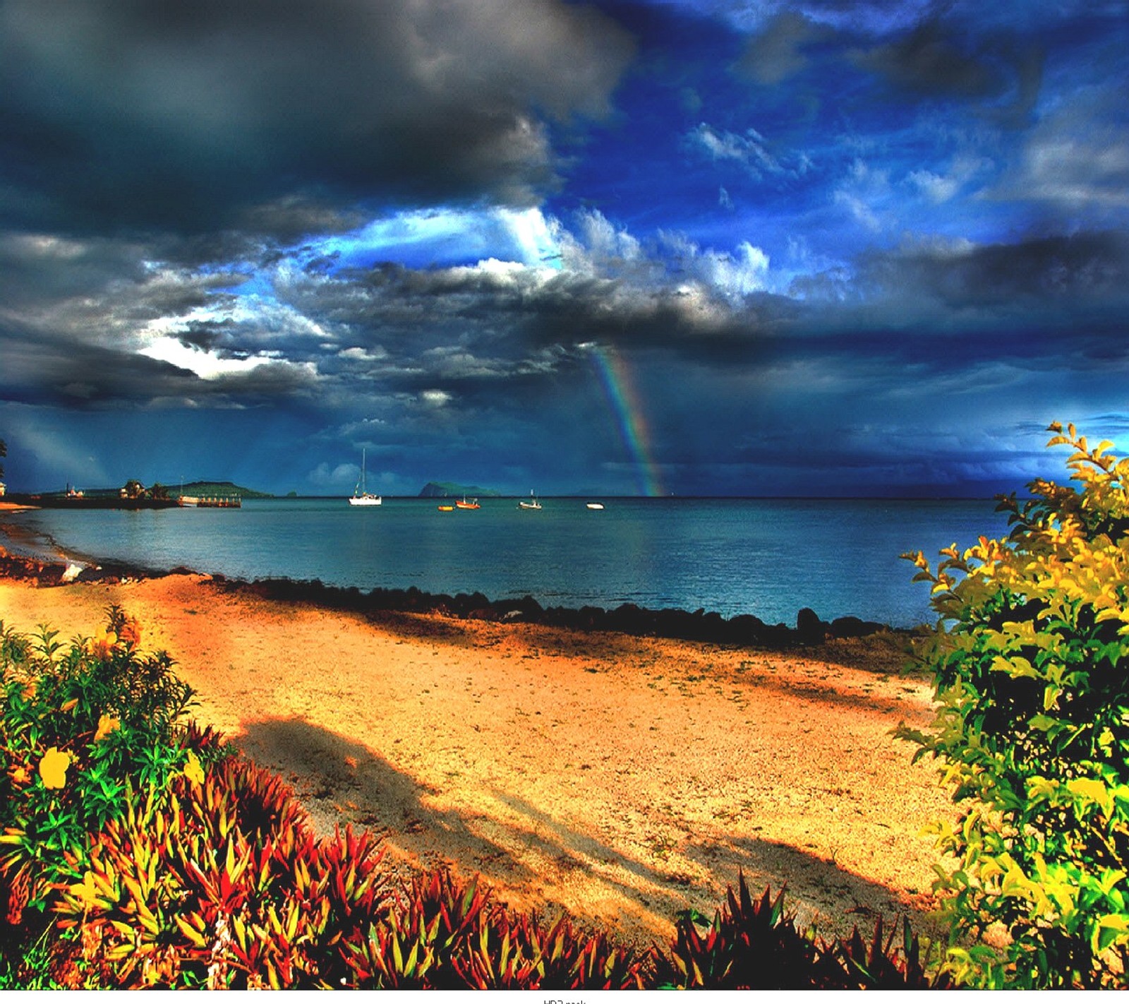 There is a rainbow in the sky over a beach and water (nature)