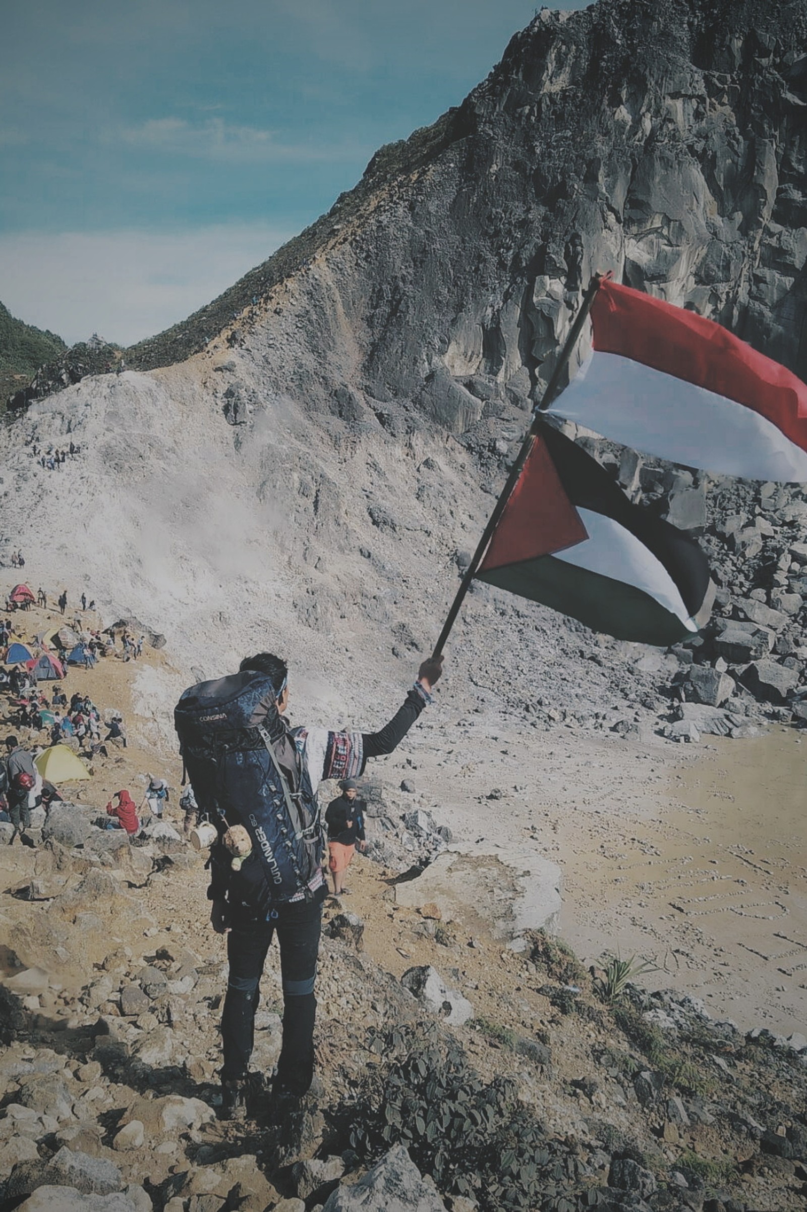 Il y a un homme tenant un drapeau sur une colline rocheuse (bon, randonneur, indonésie, montagne, palestina)