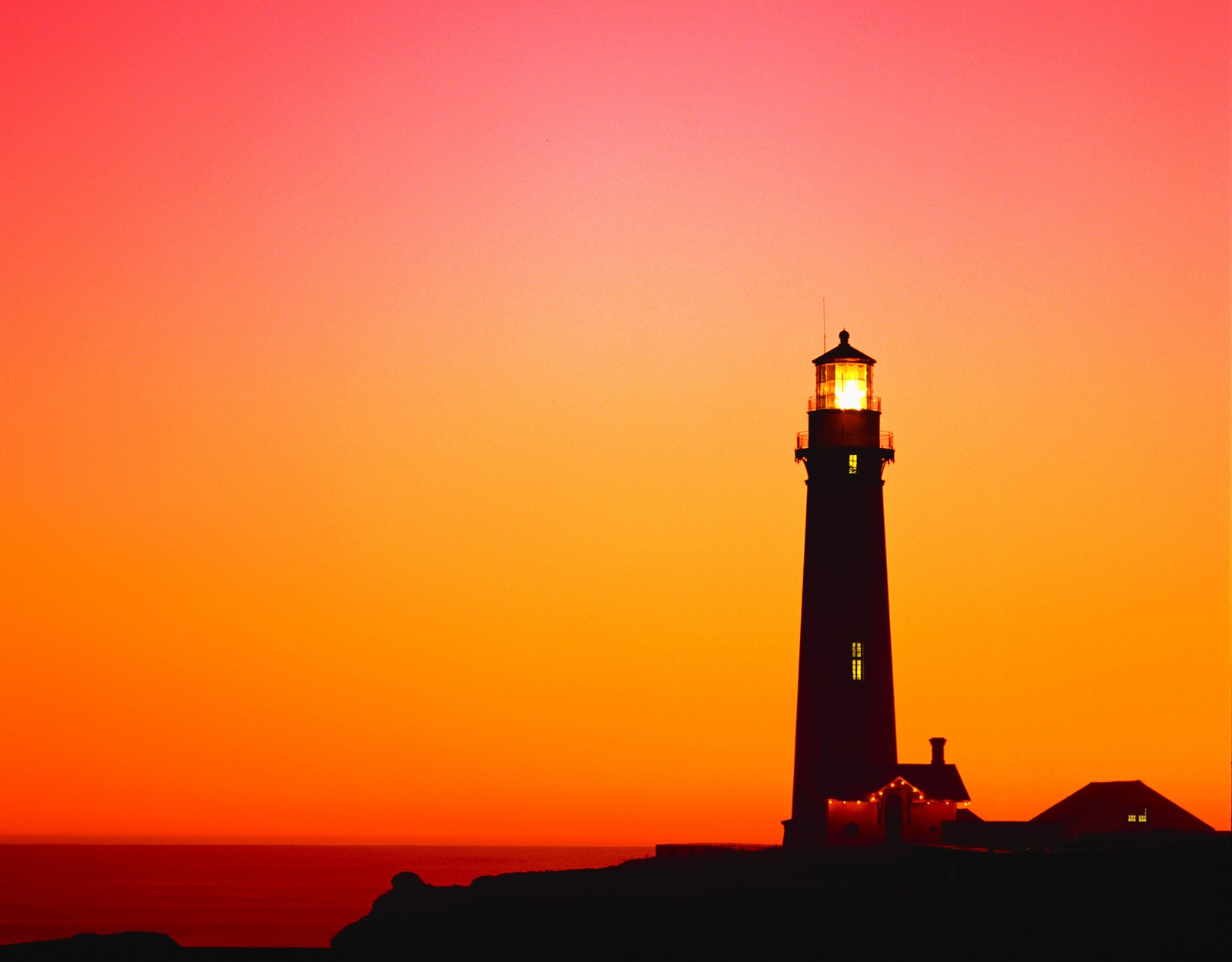 Vista panorâmica de um farol ao pôr do sol com um céu laranja brilhante (farol, por do sol, torre, crepúsculo, anoitecer)