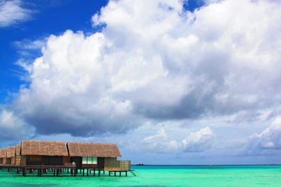 Tranquilo resort de Maldivas con vista a un océano tranquilo bajo un cielo de nubes cúmulo