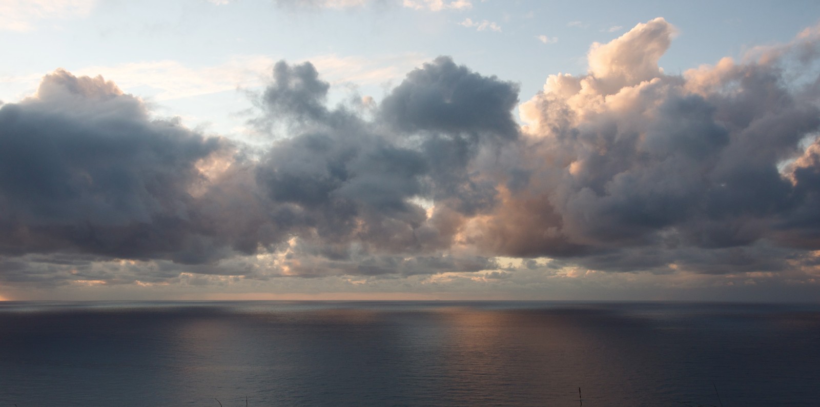 Des nuages couvrent le ciel au-dessus de l'océan et un bateau est dans l'eau (cumulus, coucher de soleil, nuage, horizon, mer)