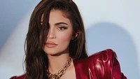 Kylie Jenner em um impressionante conjunto vermelho, exibindo sua beleza e estilo característicos em uma cativante sessão de fotos.