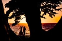 Casal em silhueta dançando ao pôr do sol à beira da água