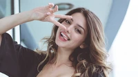 Celine Farach sonriendo juguetonamente con atuendo elegante