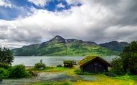 Paisagem serena de alta montanha ao lado de um fiorde com reflexos de montanhas e céu nublado