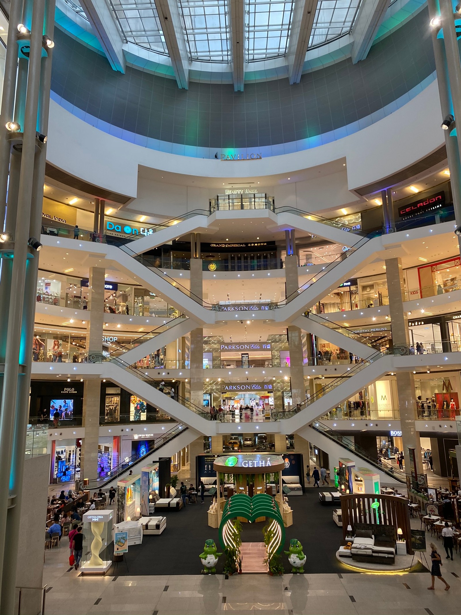 Multitudes de personas caminando por un centro comercial con un reloj (centro comercial, multitud, escalera mecánica, iluminación, arquitectura)