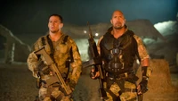 Channing Tatum and Dwayne Johnson as military soldiers ready for action in a dramatic setting.