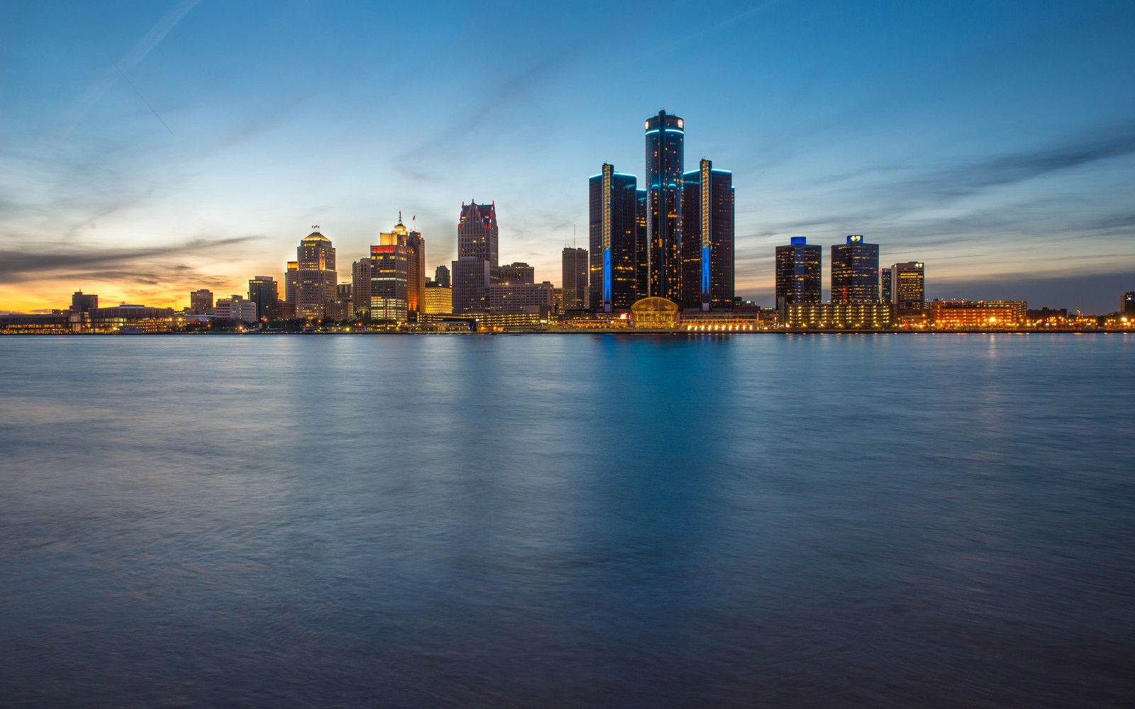 Vista aérea de un horizonte de ciudad al atardecer con un cuerpo de agua (detroit, ciudad, paisaje urbano, panorama, área urbana)