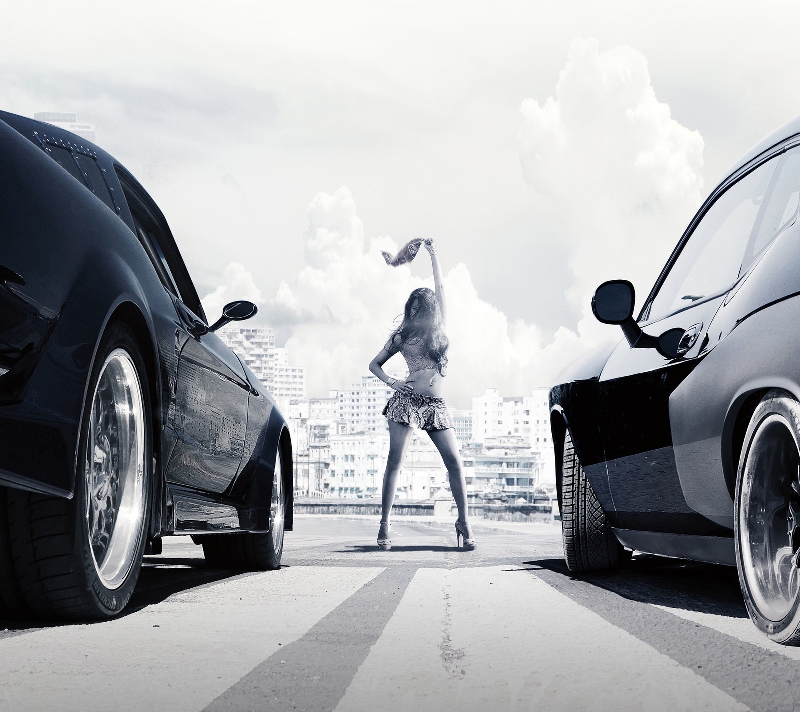 There is a woman standing next to two cars on the street (cars, city, fast and furious, fate, girl)