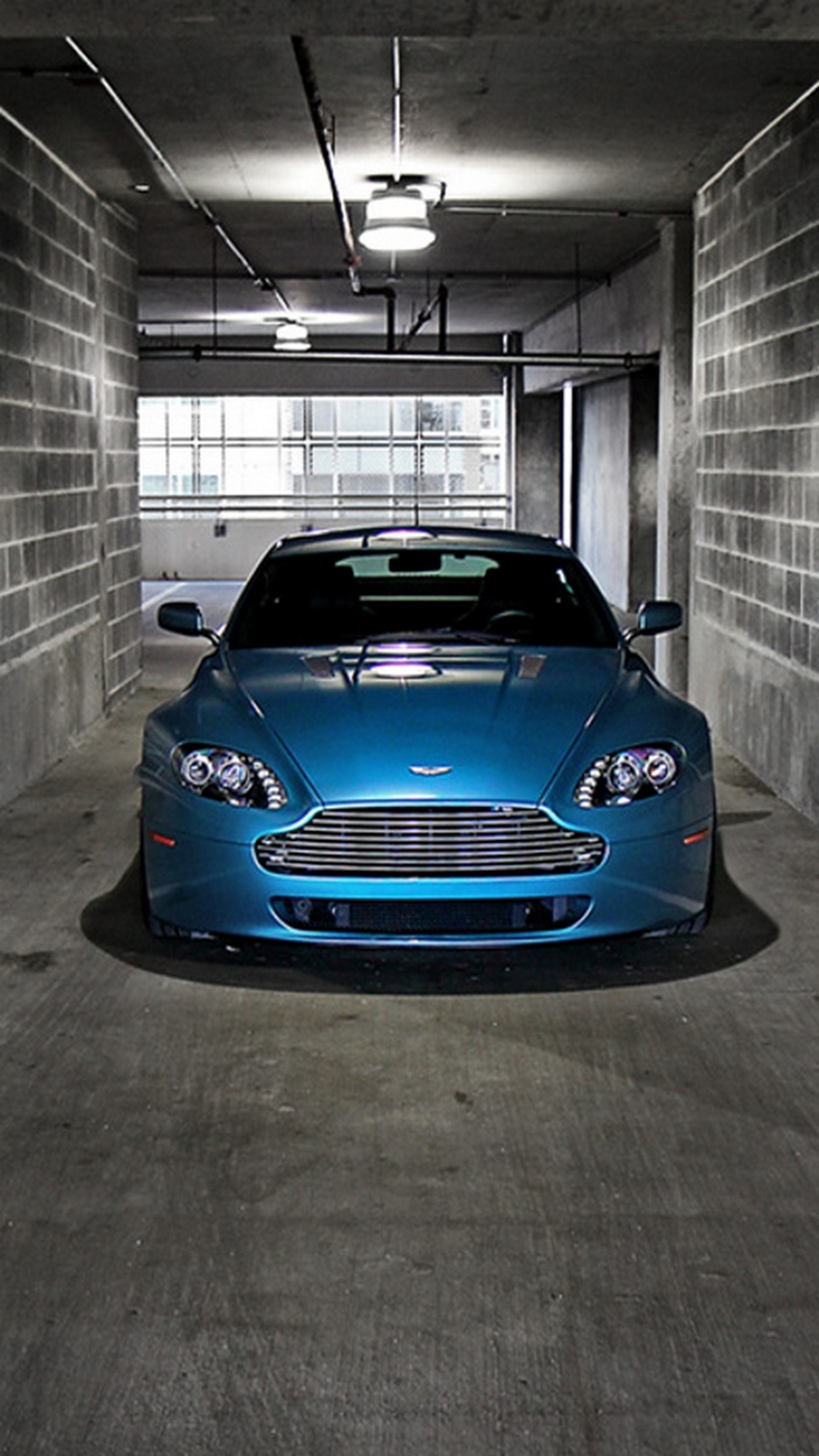 Arafed blue car in a parking garage with a brick wall (blue, car, vehicle)