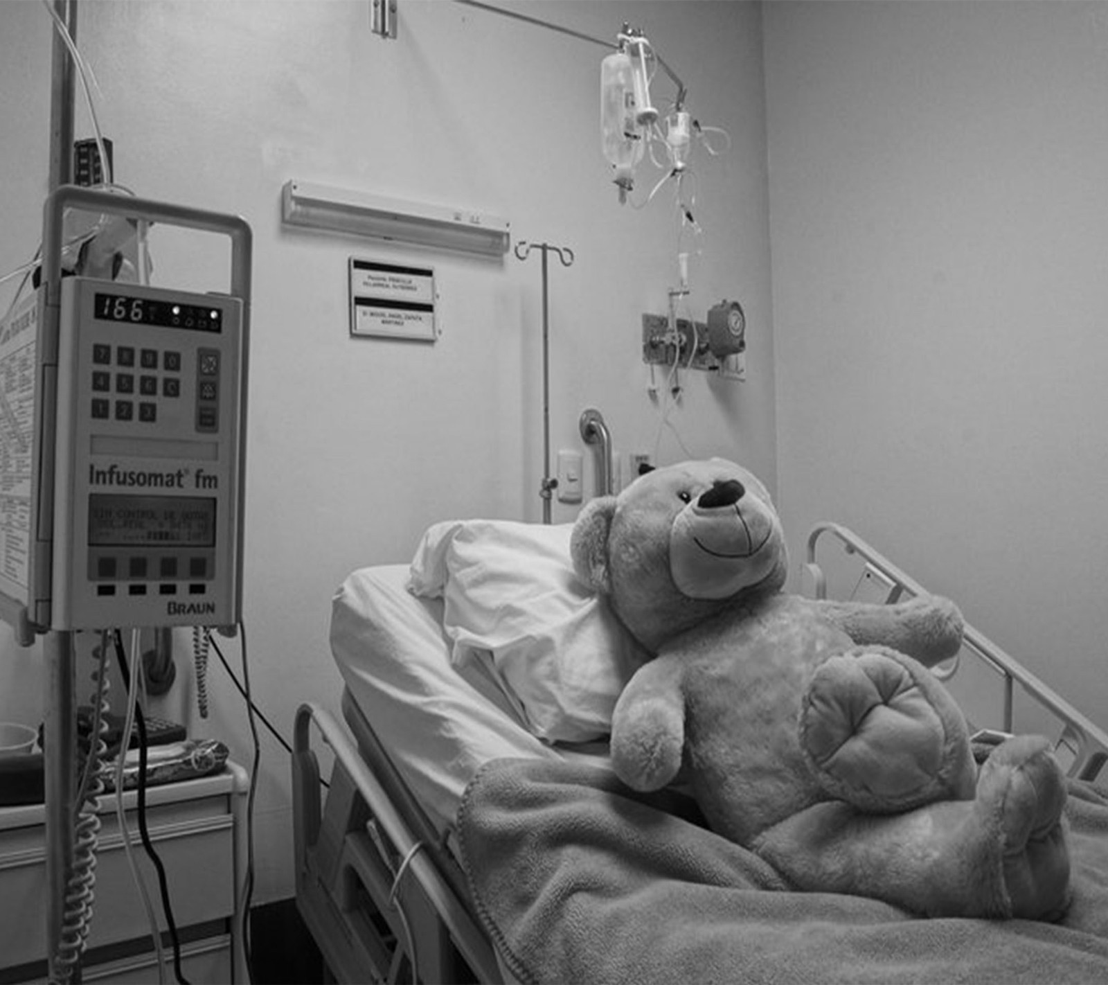 Un oso de peluche sentado en una cama de hospital (enfermo, ted)