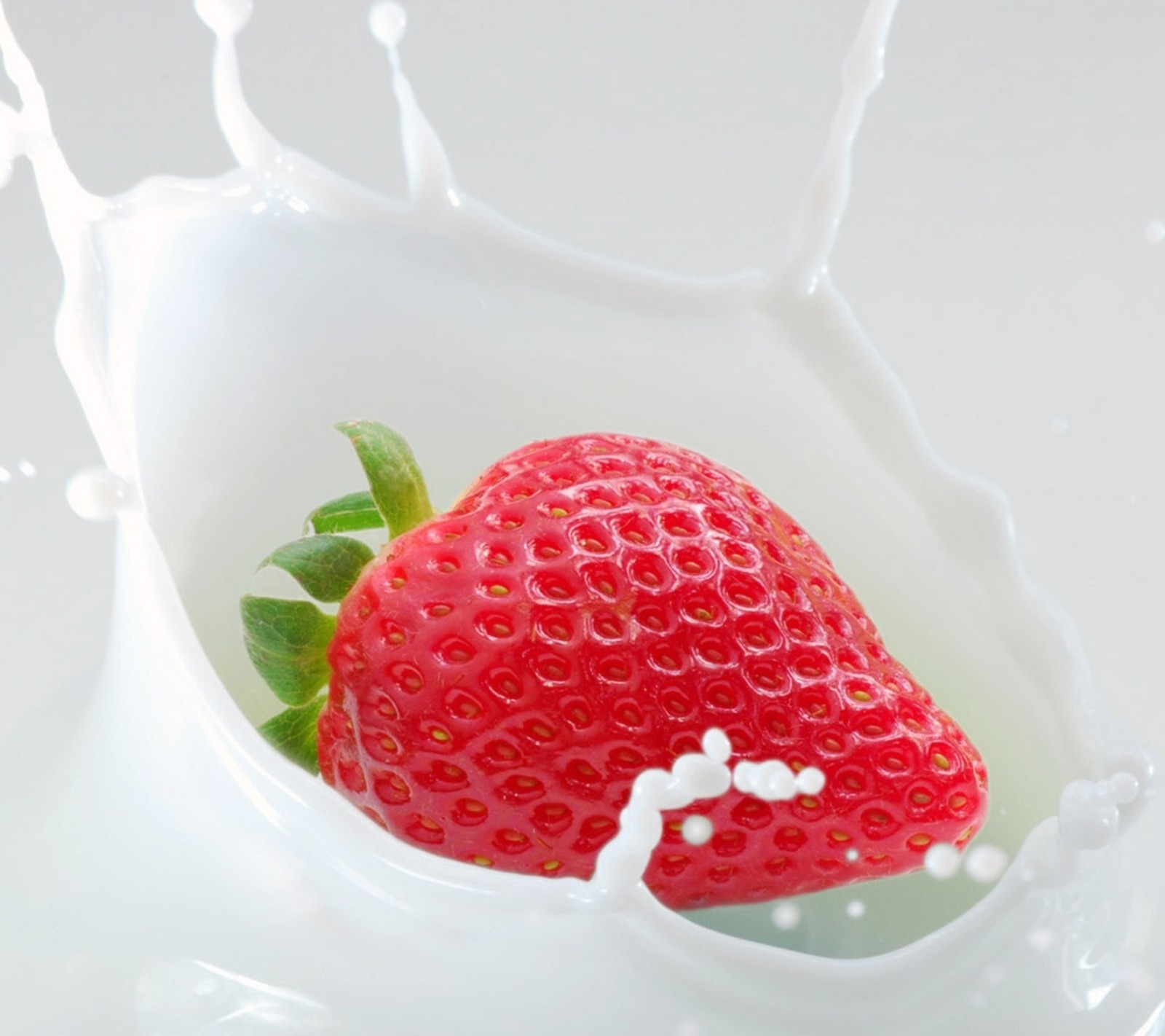 Araffe strawberry in a milk splash with a green leaf (2160x1920, wallpaper)