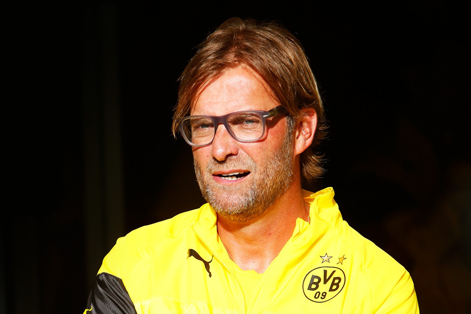 Un hombre con una camisa amarilla y gafas de pie frente a una multitud. (liverpool fc, liverpool f c, gerente de fútbol, amarillo, gafas)