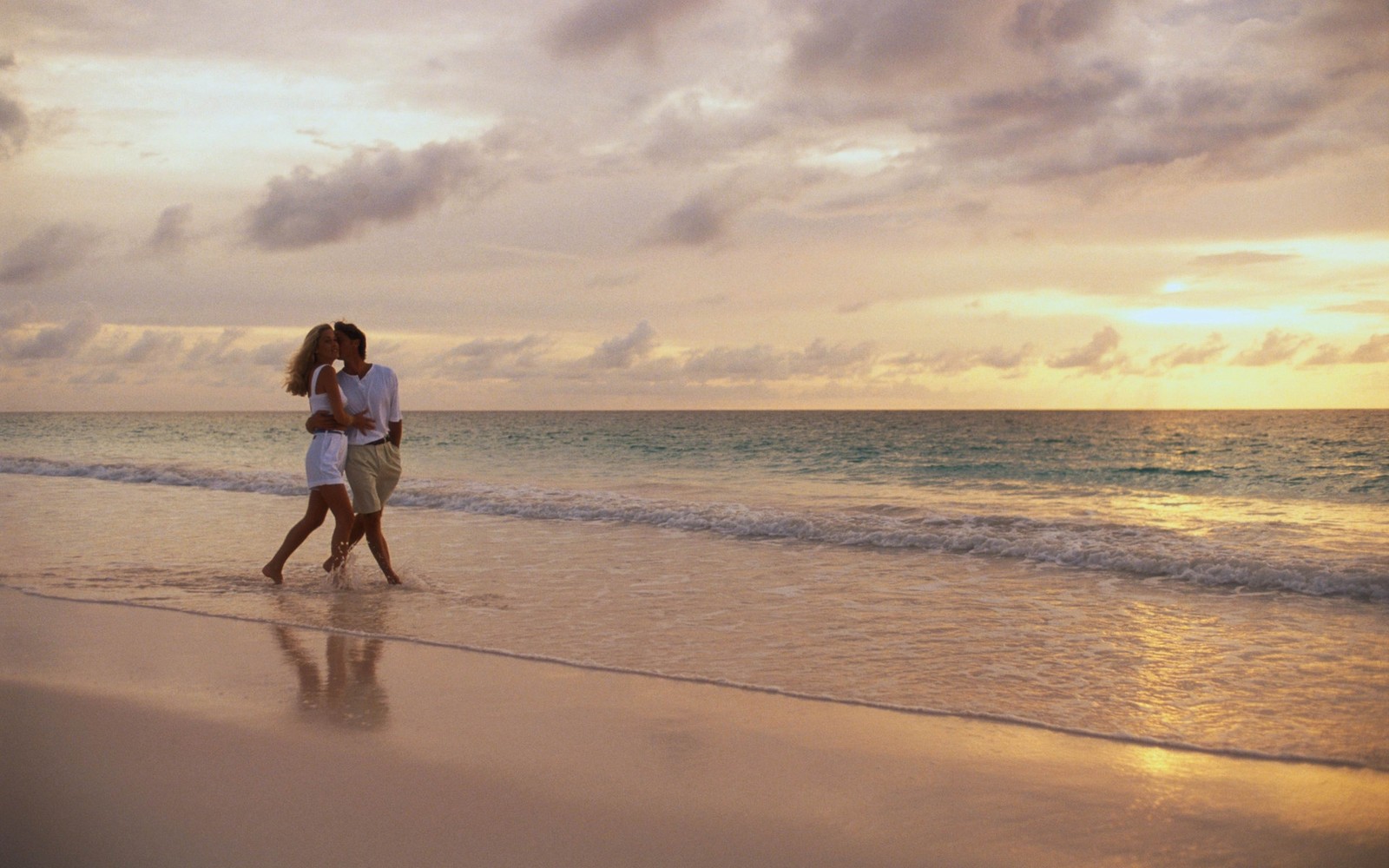 There are two people walking on the beach at sunset (couple, beach, sea, ocean, vacation)