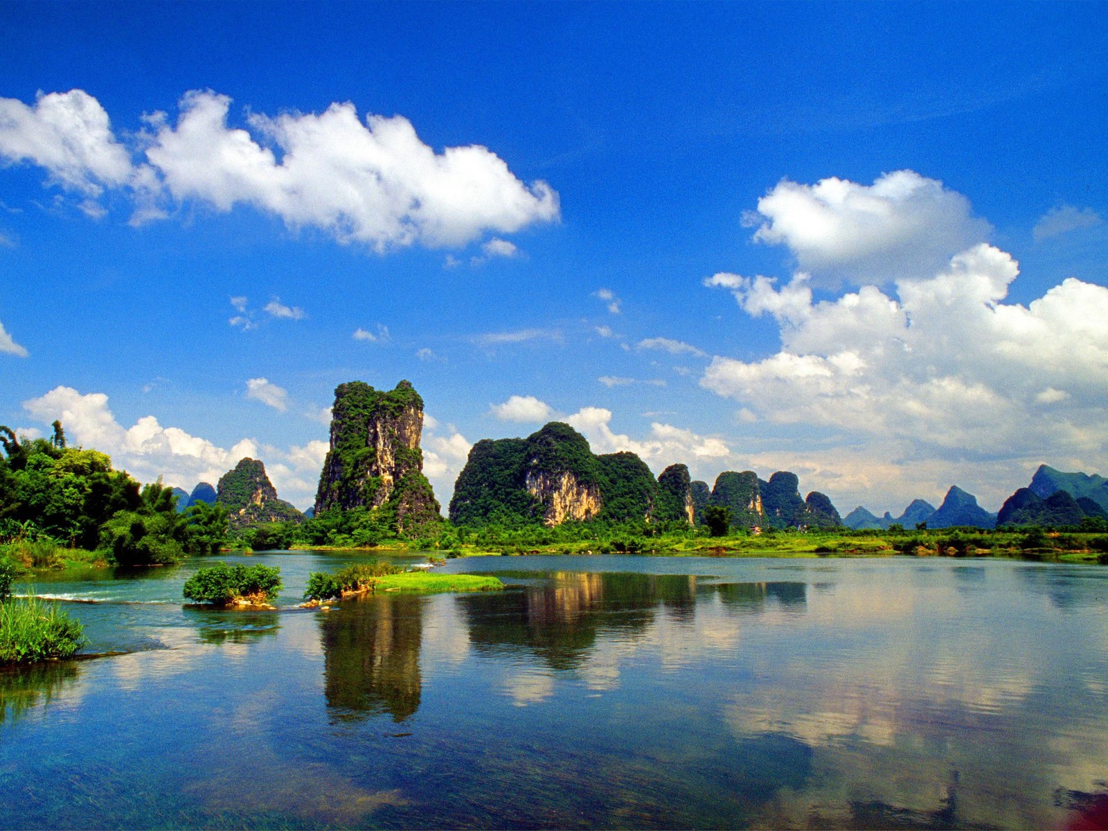 A view of a river with a boat in it and mountains in the background (nature, reflection, cloud, daytime, tourist attraction)