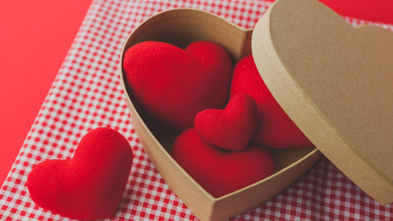 Il y a deux cœurs rouges dans une boîte en forme de cœur sur une table (saint valentin, 14 février, cœur, rouge, amour)