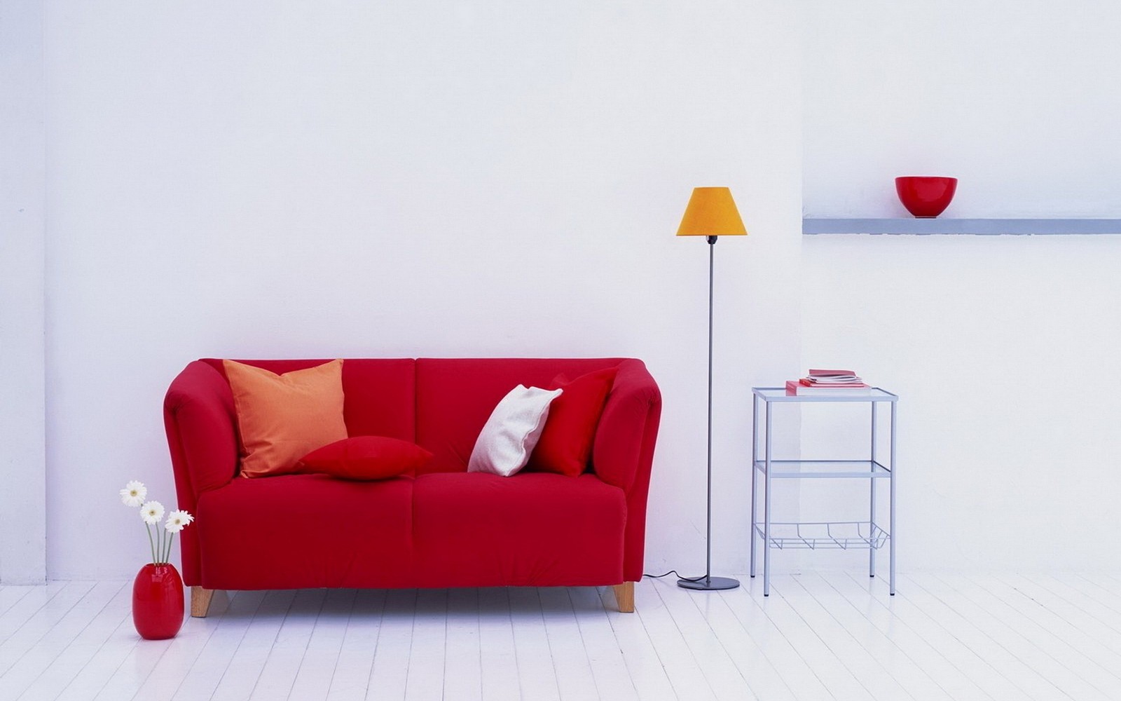 Un primer plano de un sofá rojo en una habitación blanca con una estantería. (muebles, rojo, diseño de interiores, mesa, sofá cama)