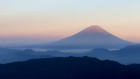 Majestosa Montanha Fuji ao amanhecer, emoldurada por uma serena cadeia de montanhas e suave luz da manhã.