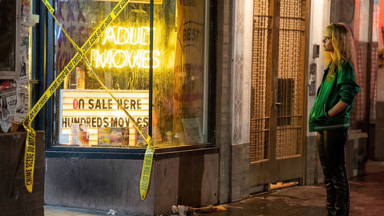 Femme arabe se tenant devant un magasin avec un panneau au néon (maxxxine, film, mia goth)