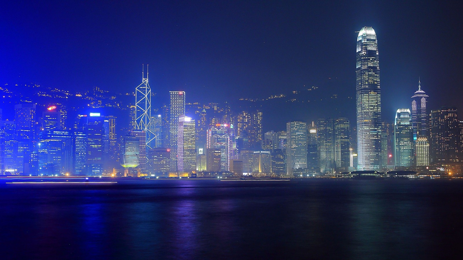 Uma vista do horizonte de uma cidade à noite com uma luz brilhante. (victoria harbour, noite, paisagem urbana, cidade, linha do horizonte)