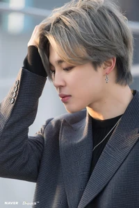 Jimin dans un élégant blazer gris, capturé pensivement contre un arrière-plan de New York.