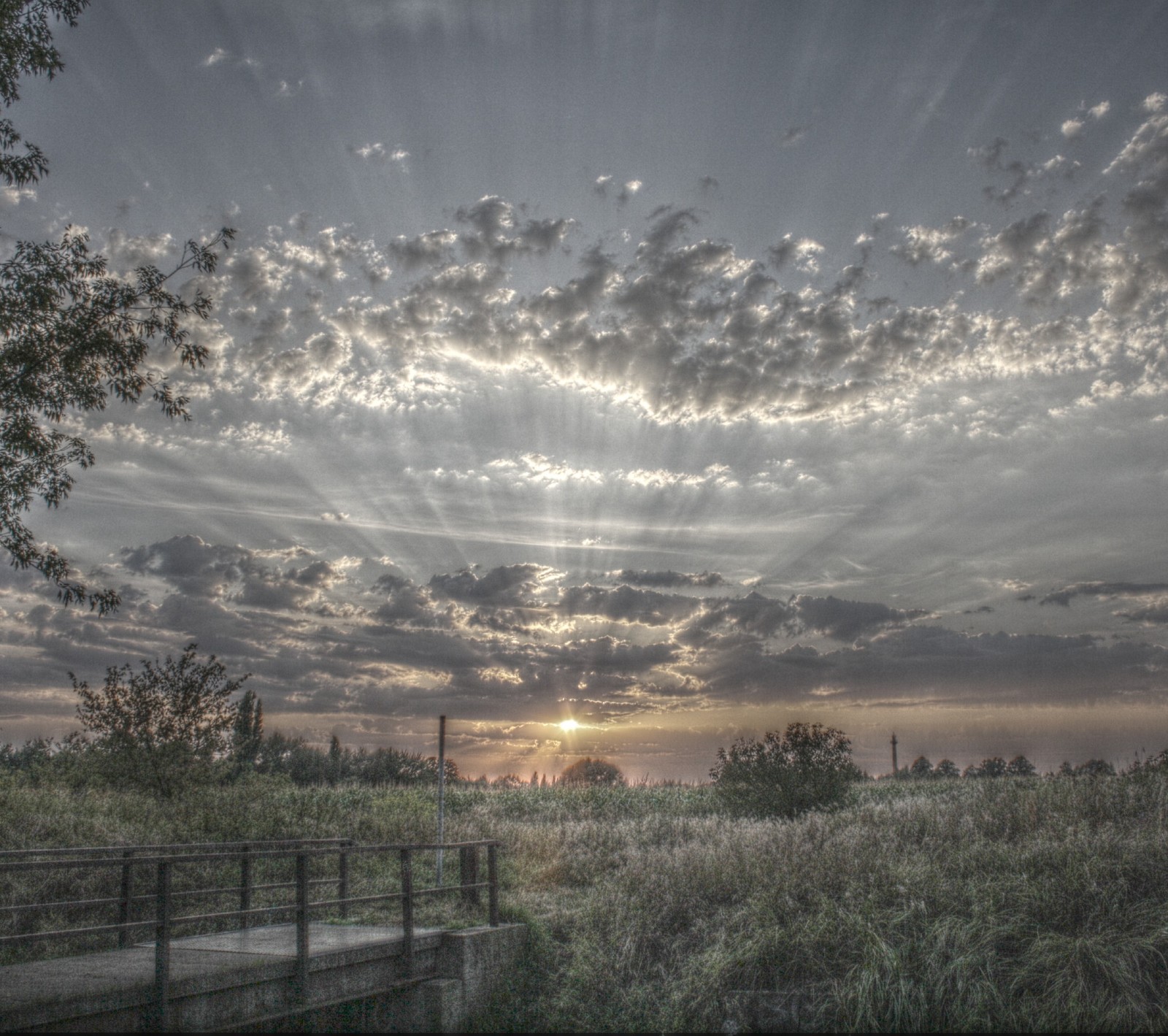 Vue aérienne d'un pont au-dessus d'un champ herbeux avec un coucher de soleil en arrière-plan (nuages, froid, paysage, matin, nature)