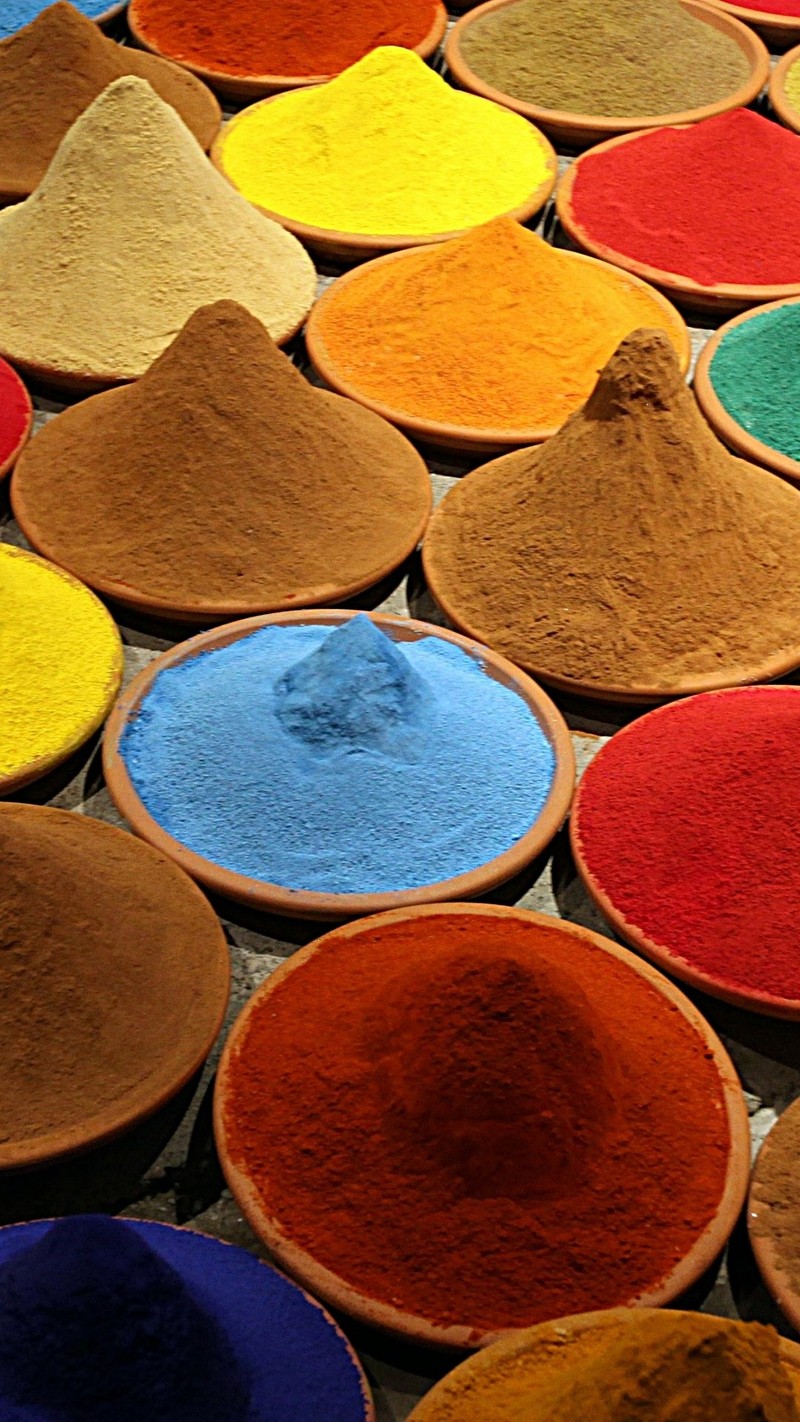 Arafed assortment of colorful powders in bowls on a table (colori, spezie)