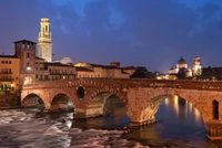 Puente histórico iluminado sobre la vía fluvial en Venecia al anochecer