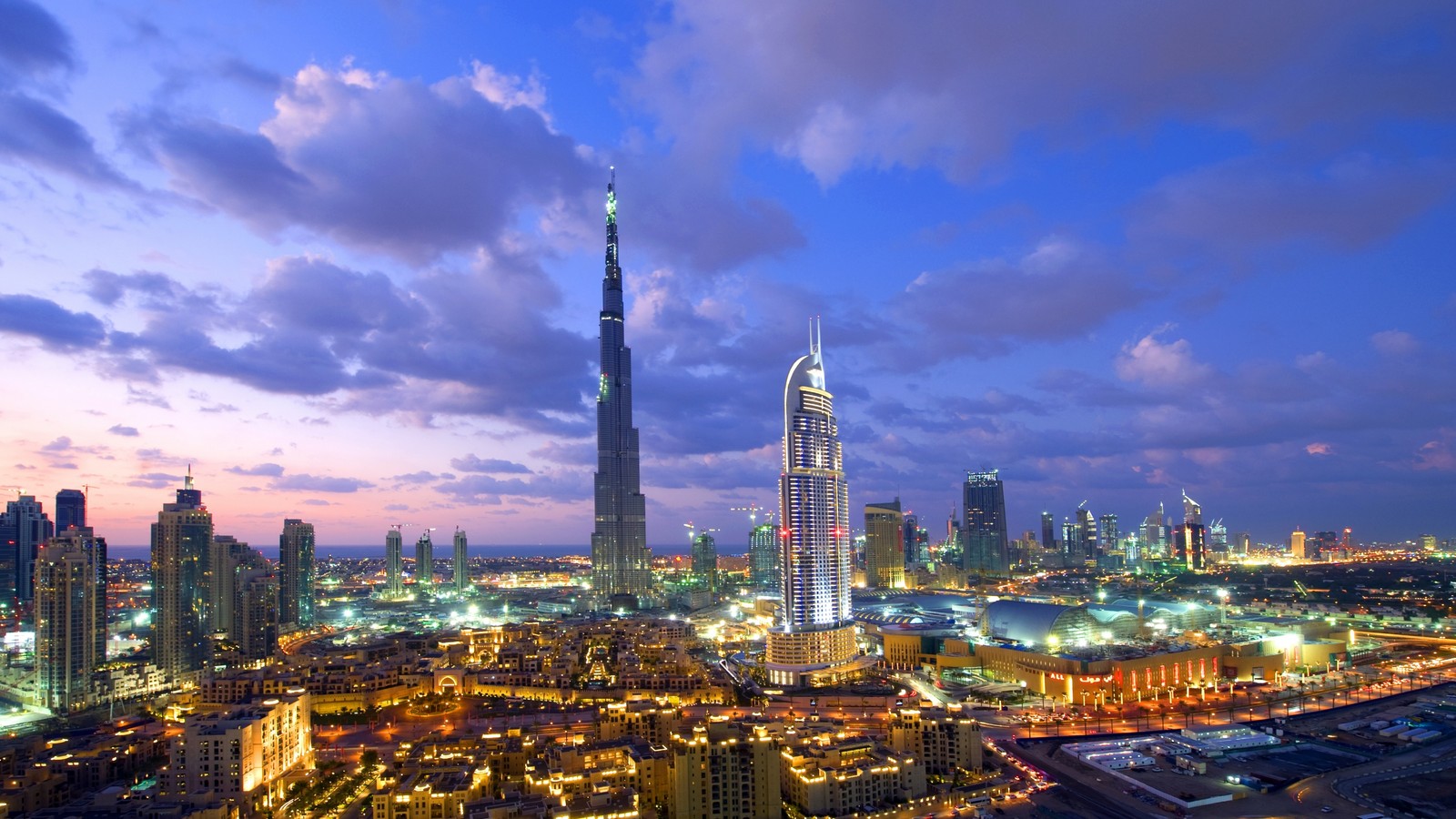 Uma vista da torre burj khalifa no meio da cidade ao entardecer (burj khalifa, cidade, paisagem urbana, arranha céus, área urbana)