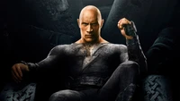 Dwayne Johnson as Black Adam, powerful and commanding, seated in a dark, brooding environment.