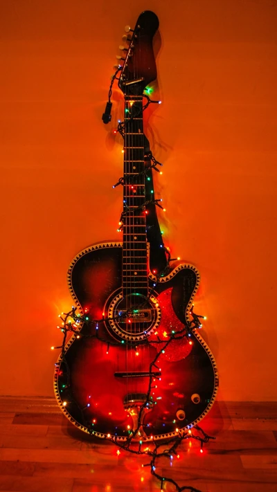 Una guitarra acústica adornada con luces de colores, apoyada contra una pared naranja cálido, mostrando un ambiente festivo y artístico.