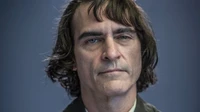 Joaquin Phoenix dans le rôle du Joker, affichant une expression sombre avec des cheveux en désordre et des yeux bleus intenses.