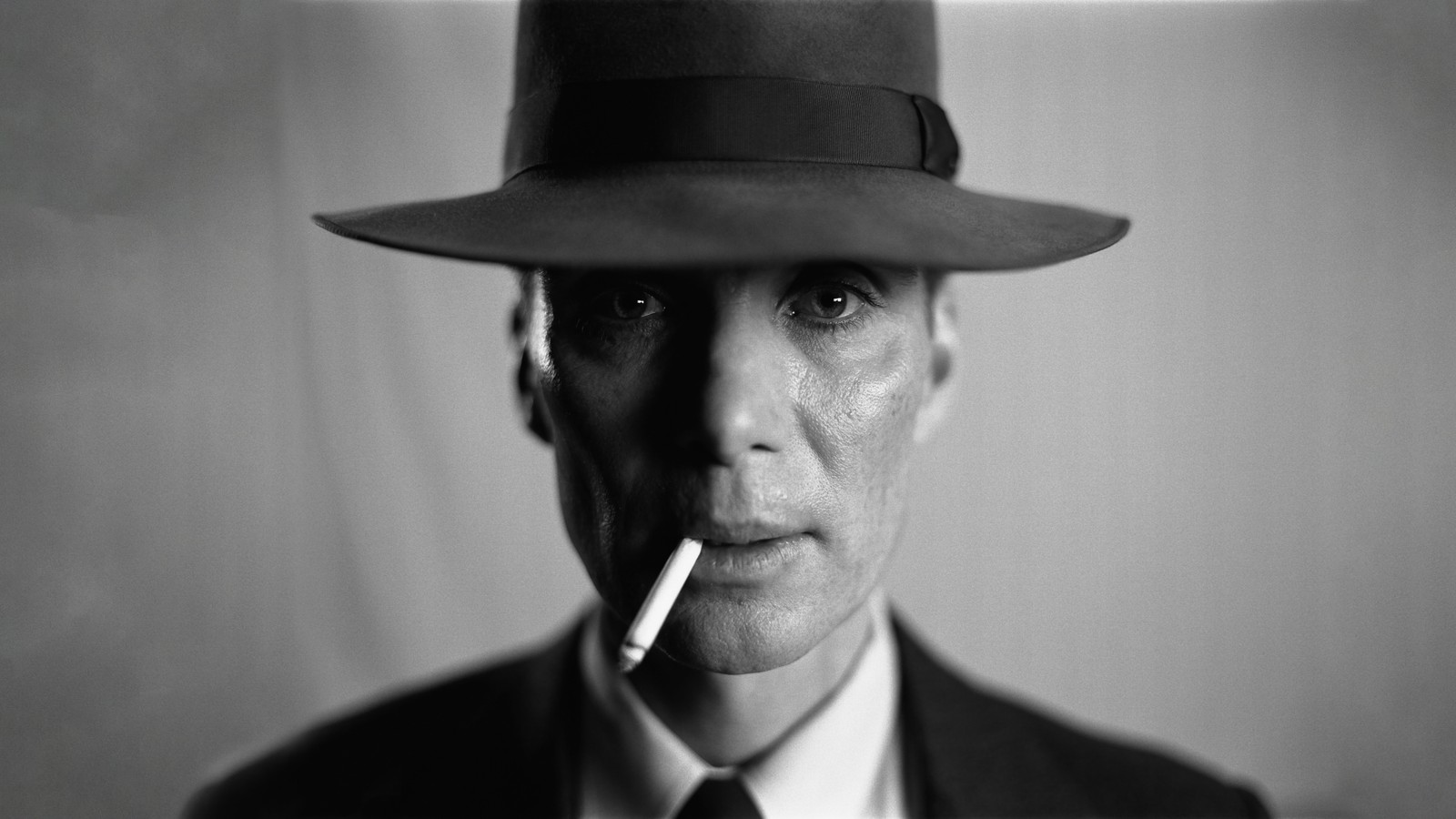 Hombre árabe en un traje y corbata con sombrero fumando un cigarrillo (oppenheimer, película, 2023, cillian murphy)