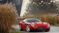 Maserati vermelho elegante com rodas de liga leve cercado pela natureza e arquitetura moderna