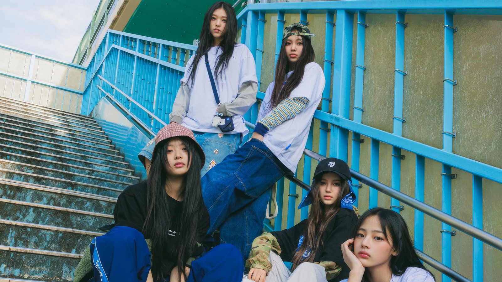 Un groupe de jeunes femmes assises sur les marches d'un bâtiment (newjeans, kpop, new jeans, groupe de filles coréen, korean girl group)