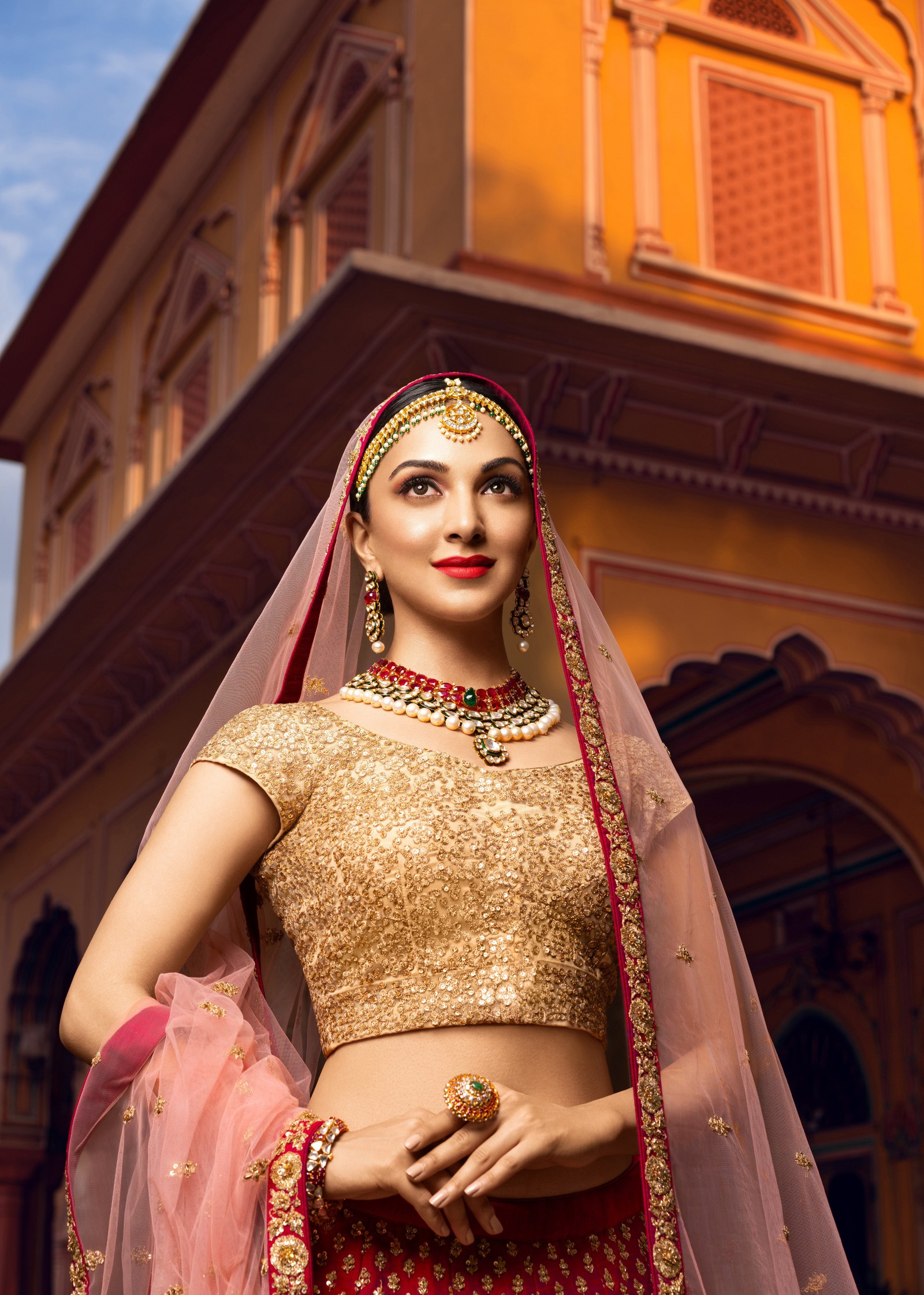 Imagen arreglada de una mujer vestida de rojo y oro posando para una foto (kiara advani, tradicional, actriz de bollywood, novia, actriz hermosa)