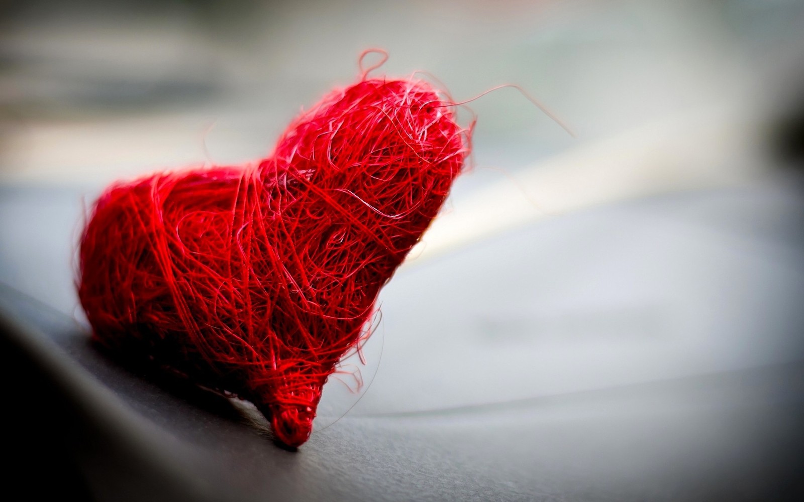 Arafed red heart on a black surface with a blurry background (red, thread, textile, heart, love)