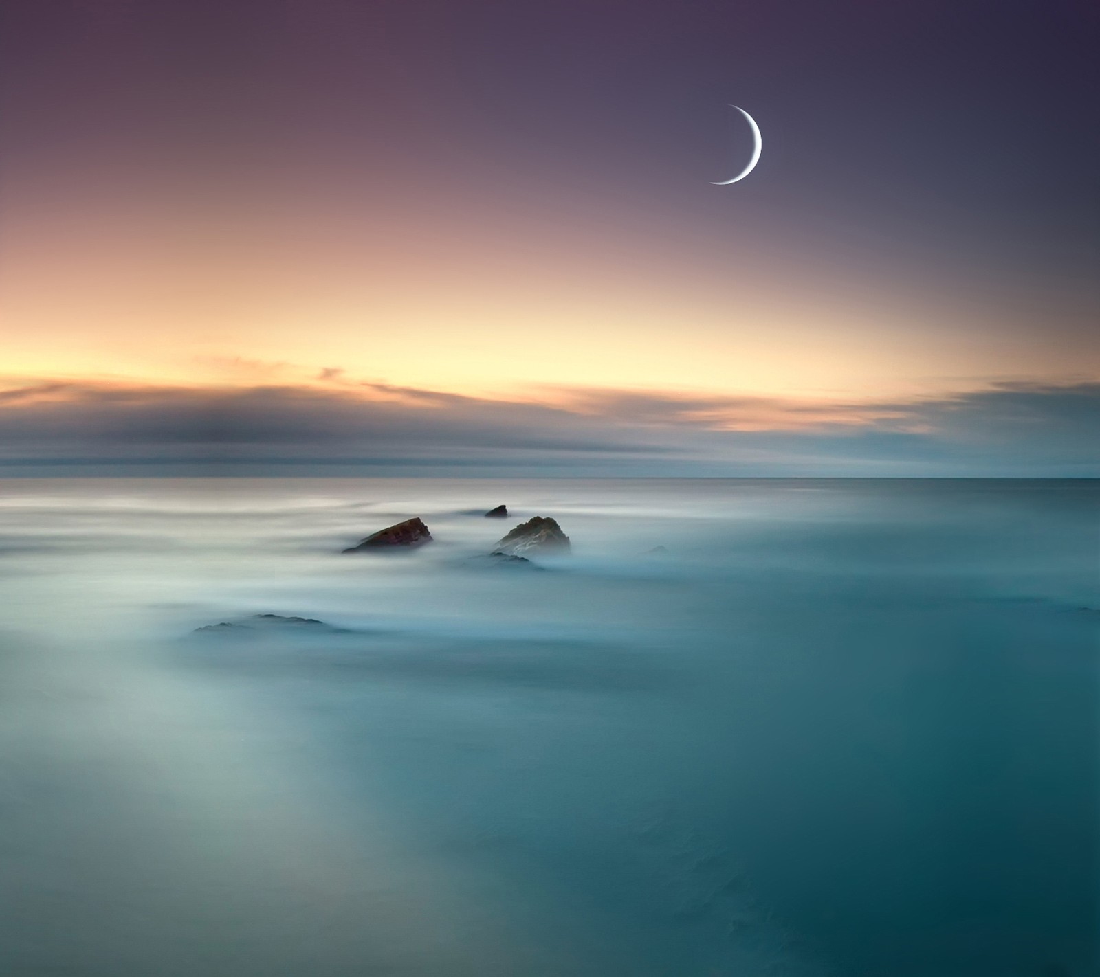 Vista de una luna poniéndose sobre el océano con rocas en primer plano. (nube, creciente, lg, montaña)