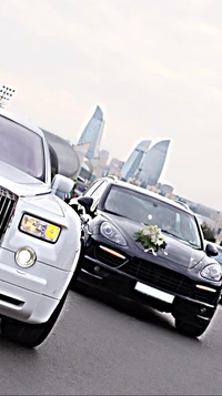 Elegant Porsche Cayenne GTS and Rolls Royce in a modern cityscape.