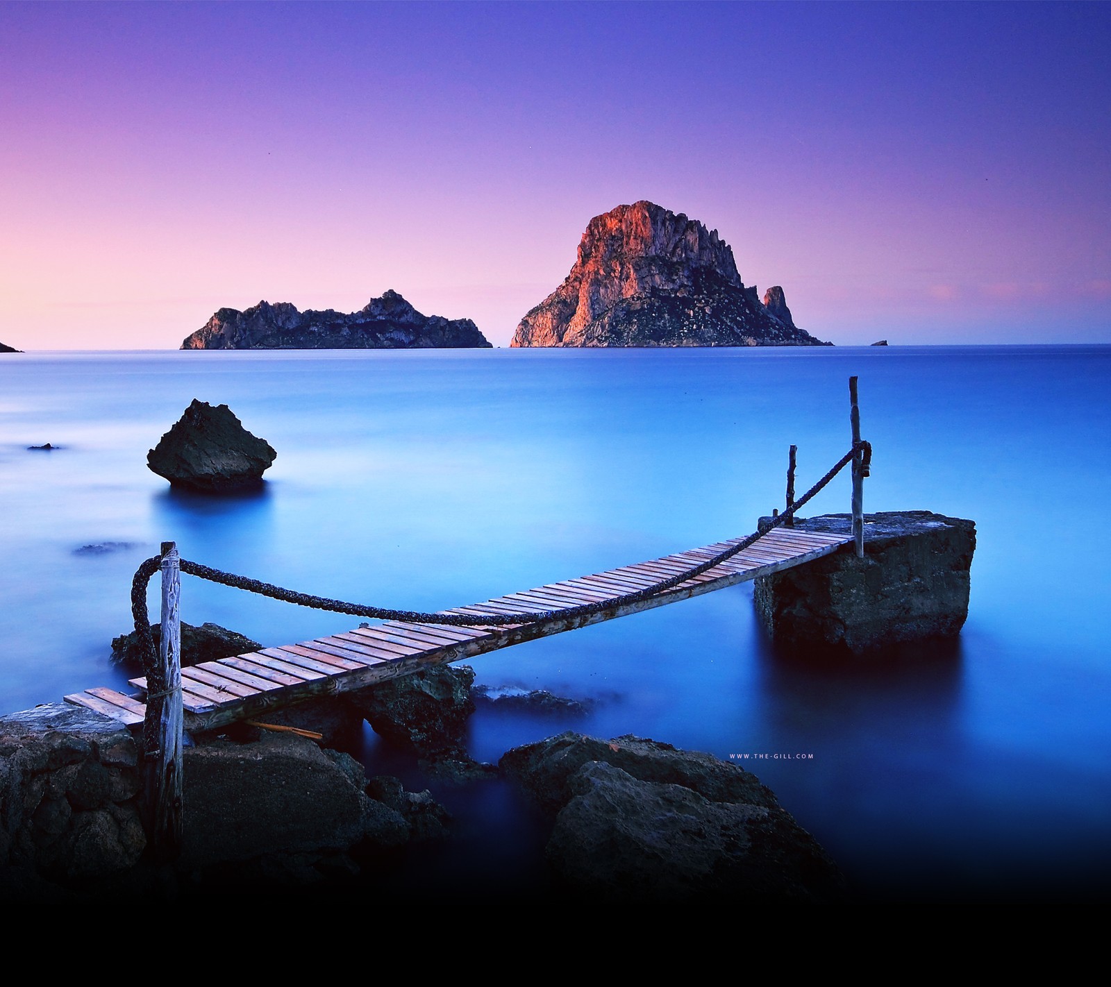 Arafed bridge over the water leading to a rocky island (beach, nature)