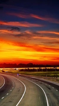 Estrada curva sob um vibrante céu amarelo ao amanhecer