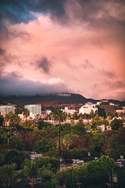 Sunset over Hollywood Hills with iconic sign and urban landscape.