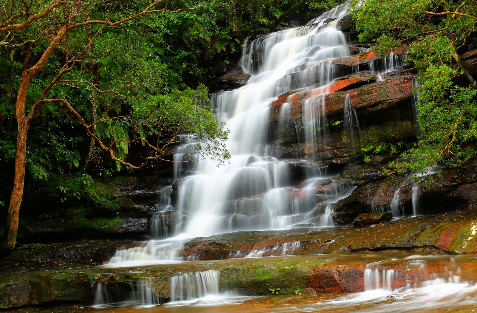 A close up of a waterfall with a few trees in the background (waterfall, body of water, water resources, nature, water)