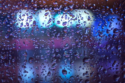 Gotas de lluvia vibrantes sobre una superficie con bokeh azul eléctrico y violeta