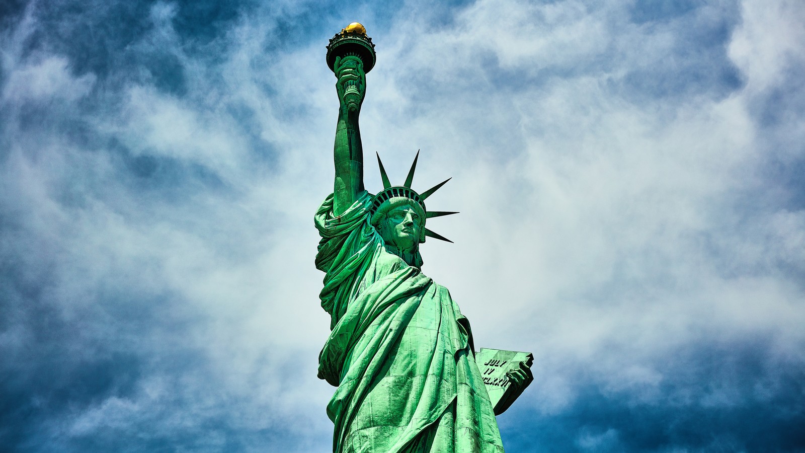 La statue de la liberté contre un ciel nuageux avec une lumière jaune (statue de la liberté, new york harbor, new york, new york city, 5k)