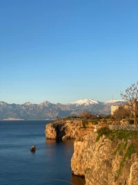 Paysage côtier serein avec des montagnes enneigées et des eaux azurées